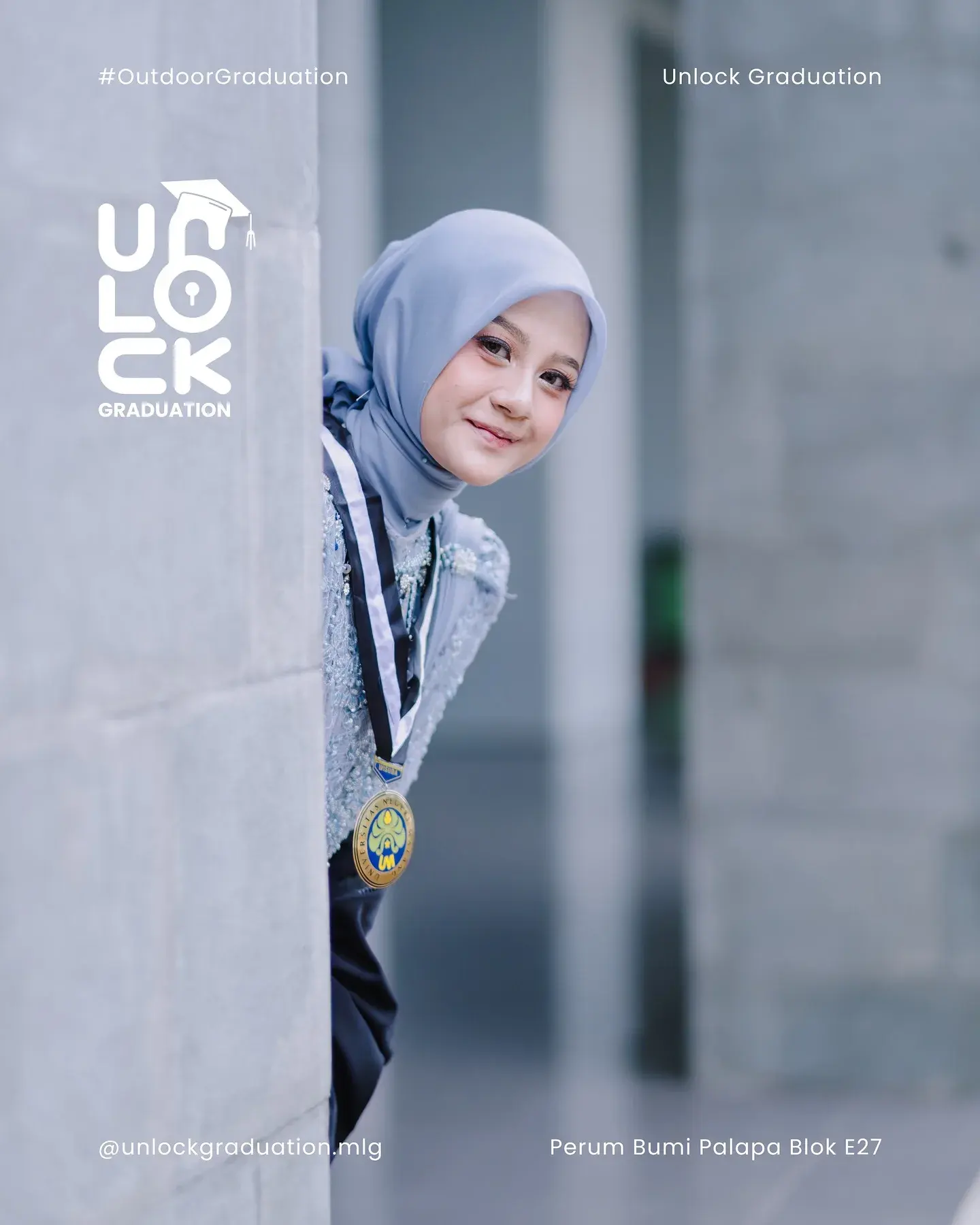 Wisudawati berhijab biru bersandar di pilar kampus