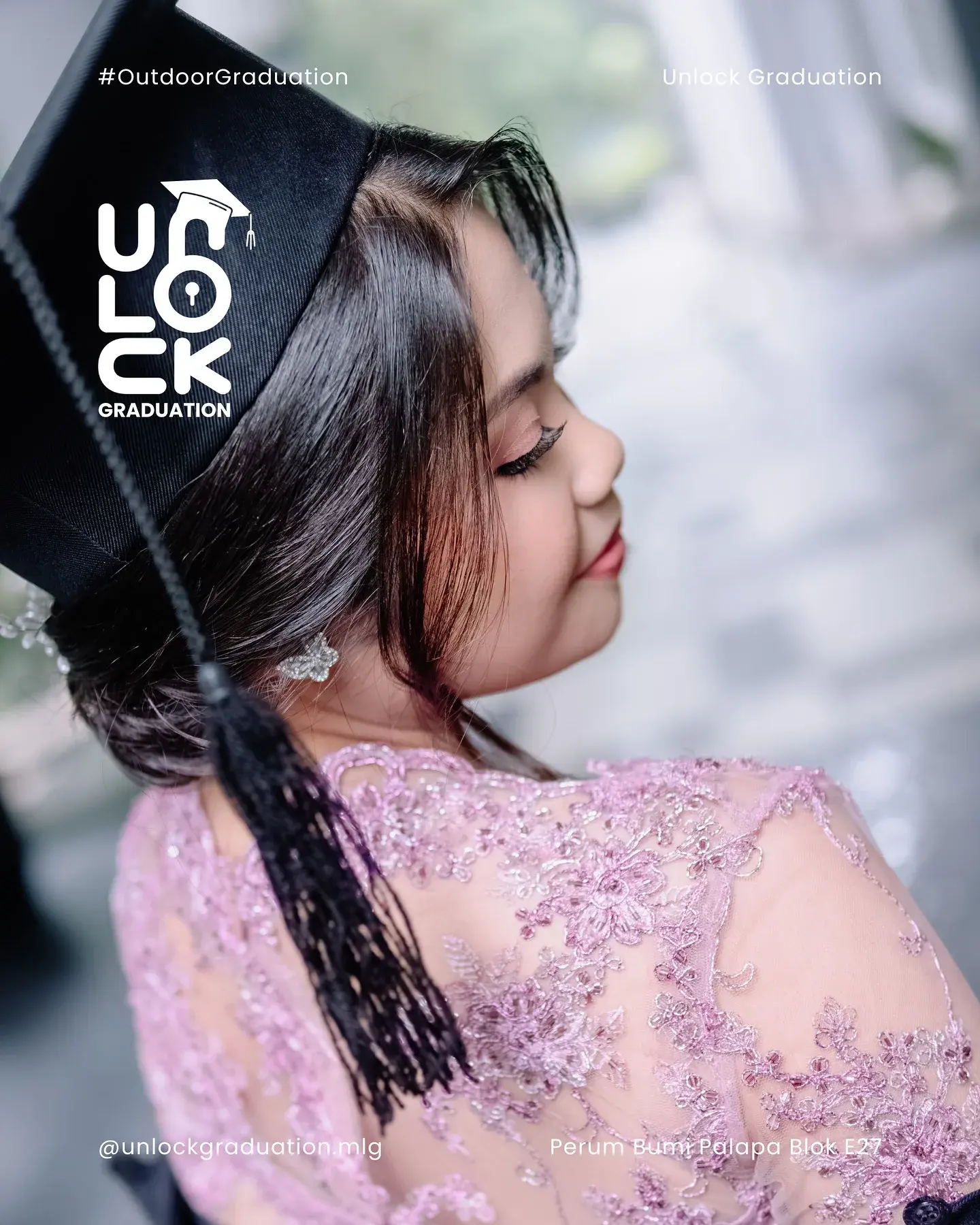 Wisudawati memegang tali toga, berkebaya merah muda