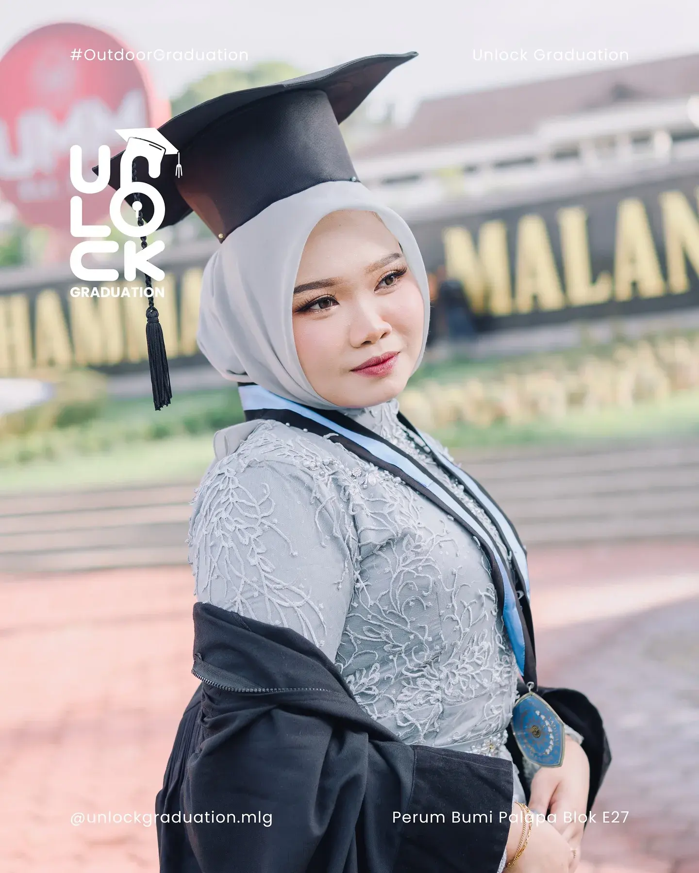 Wisudawati di depan tulisan kampus Malang