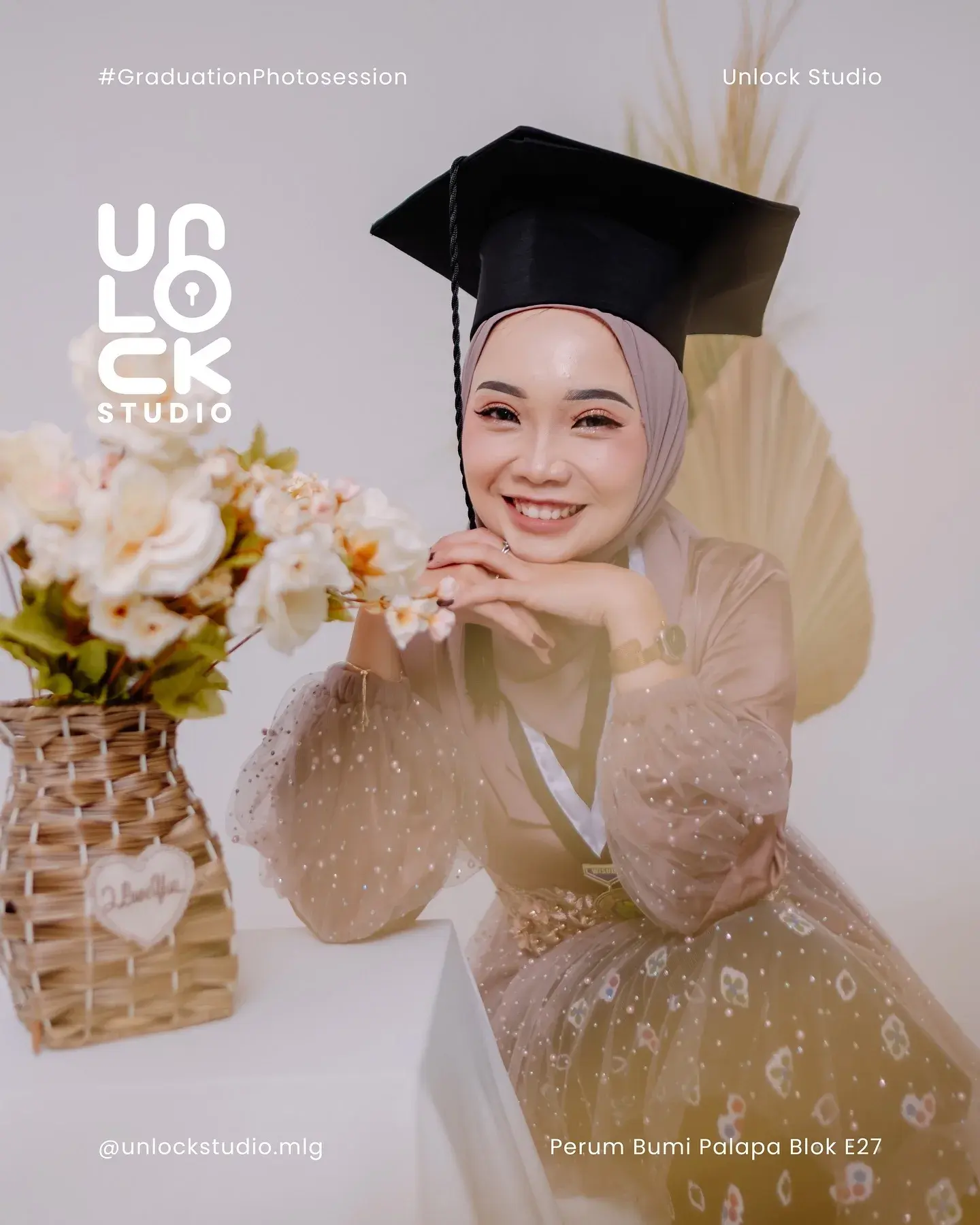 Wisudawati duduk dengan buket bunga di studio