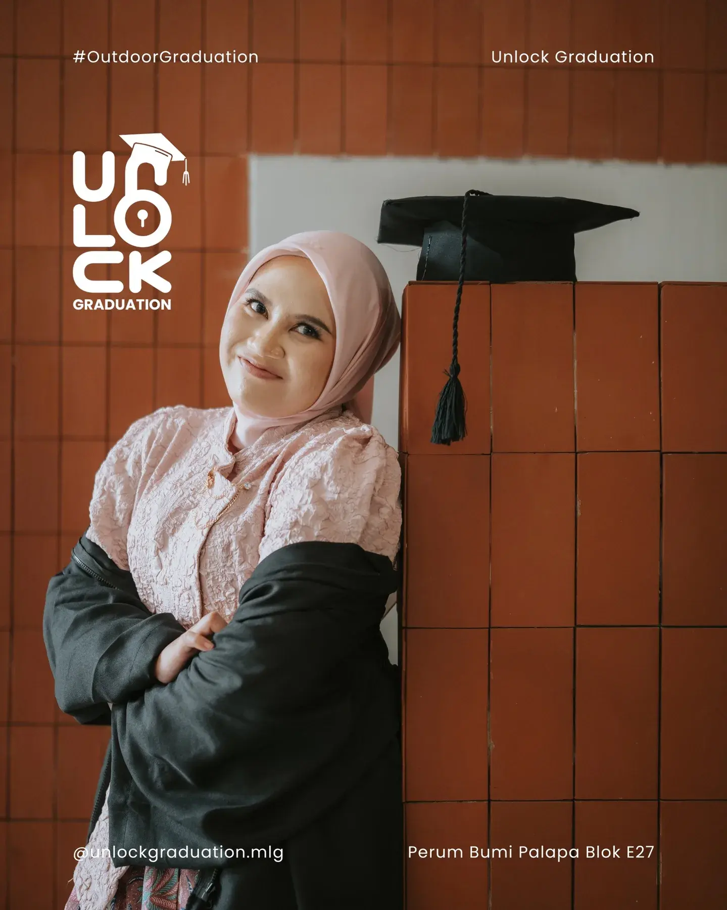 Wisudawati di depan dinding bata oranye