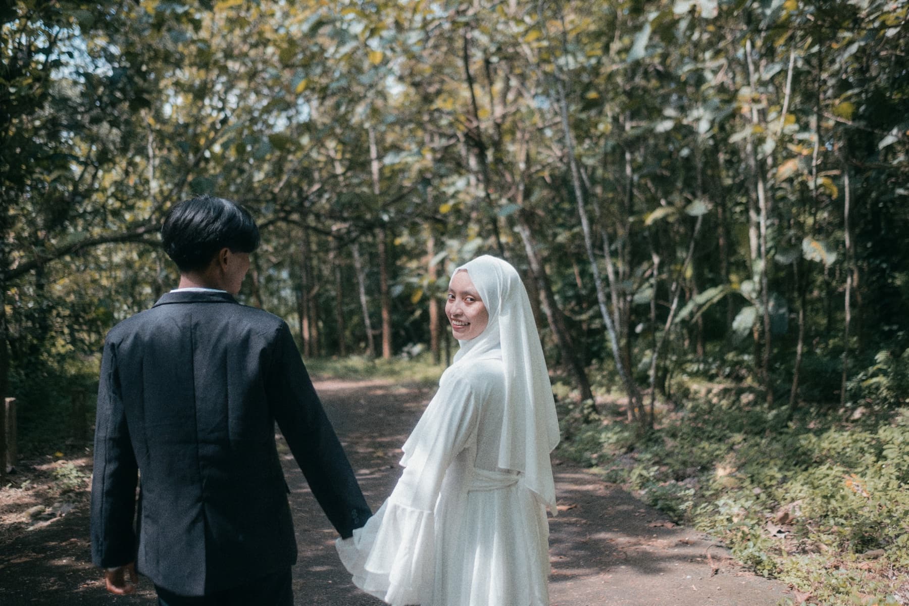 Pasangan pengantin berjalan bersama di lokasi outdoor