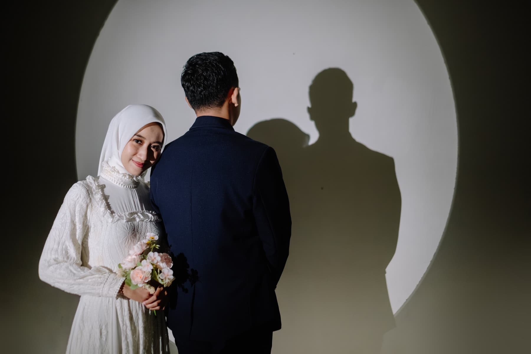 Pasangan pengantin dalam pencahayaan studio berbentuk lingkaran